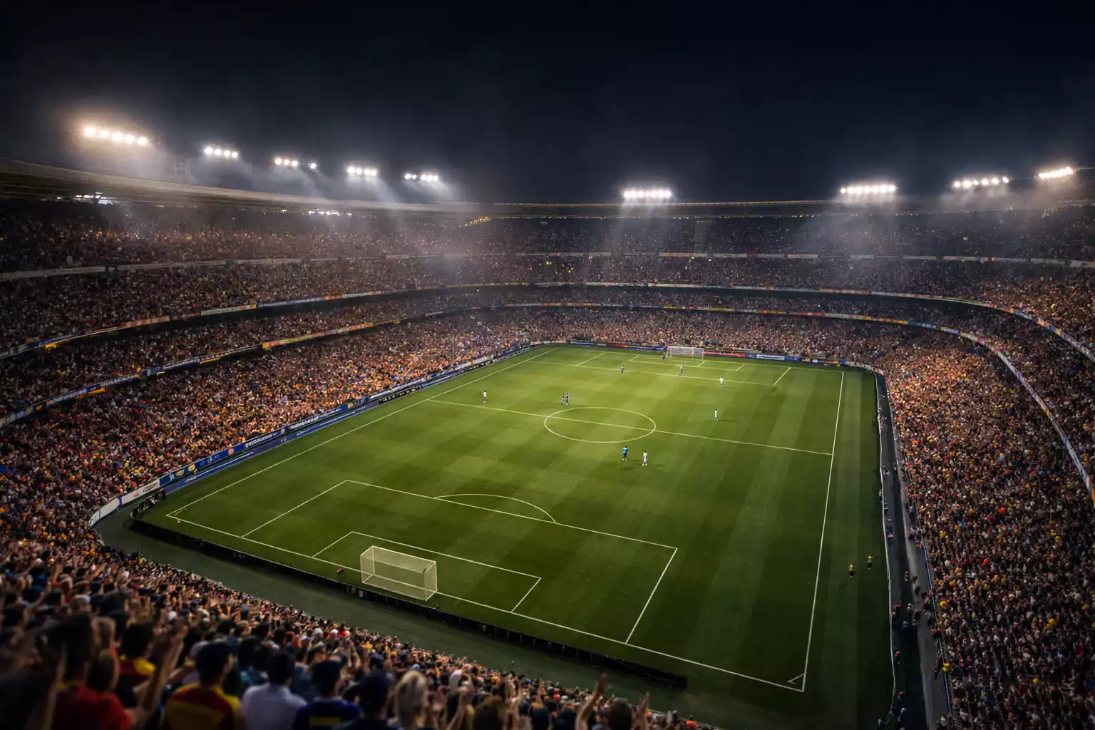 Estadio de fútbol iluminado durante un partido nocturno con aficionados en las gradas